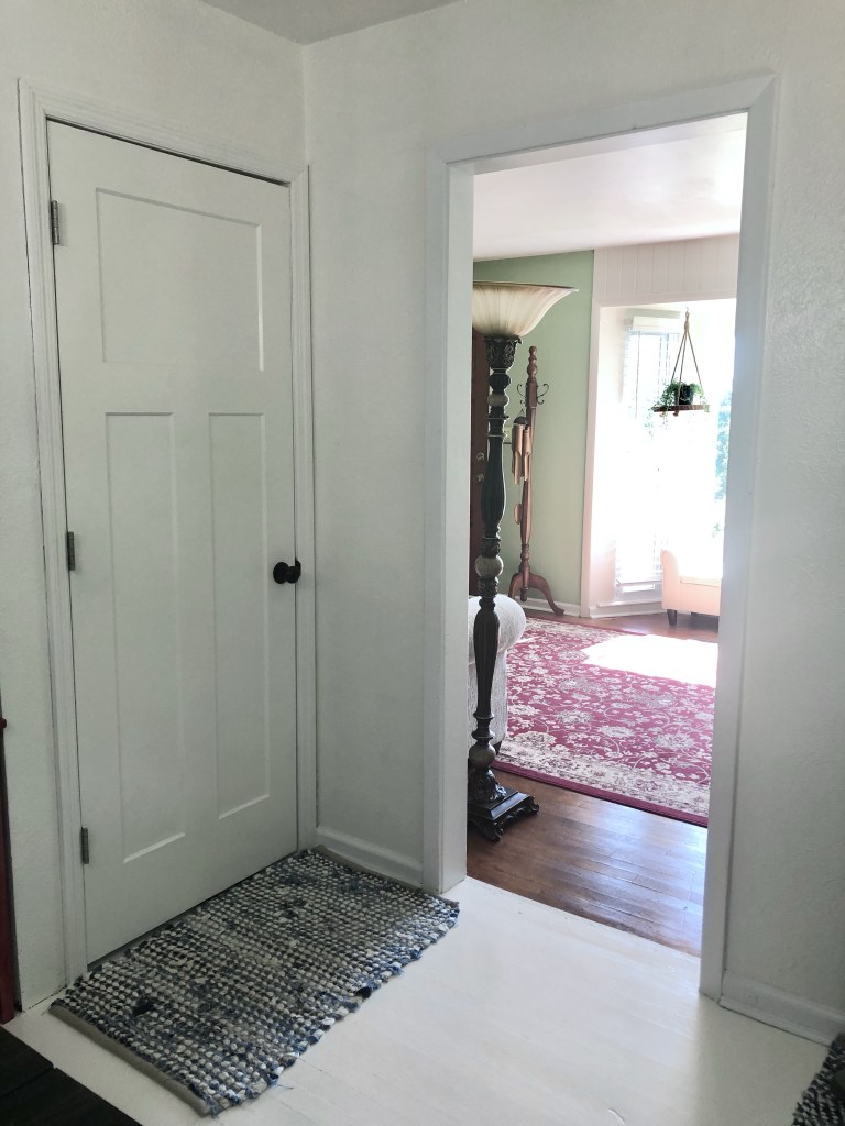 A painted white masonite door has a denim rug in front of it.