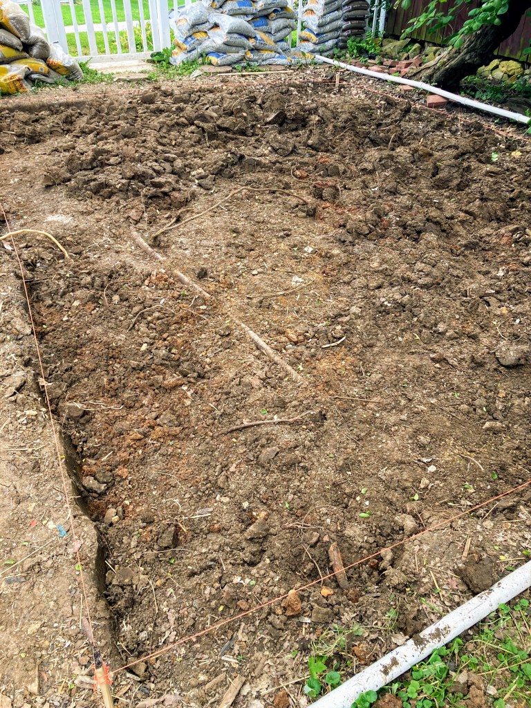 A dug up patio area is prepared before filling it with pea gravel.