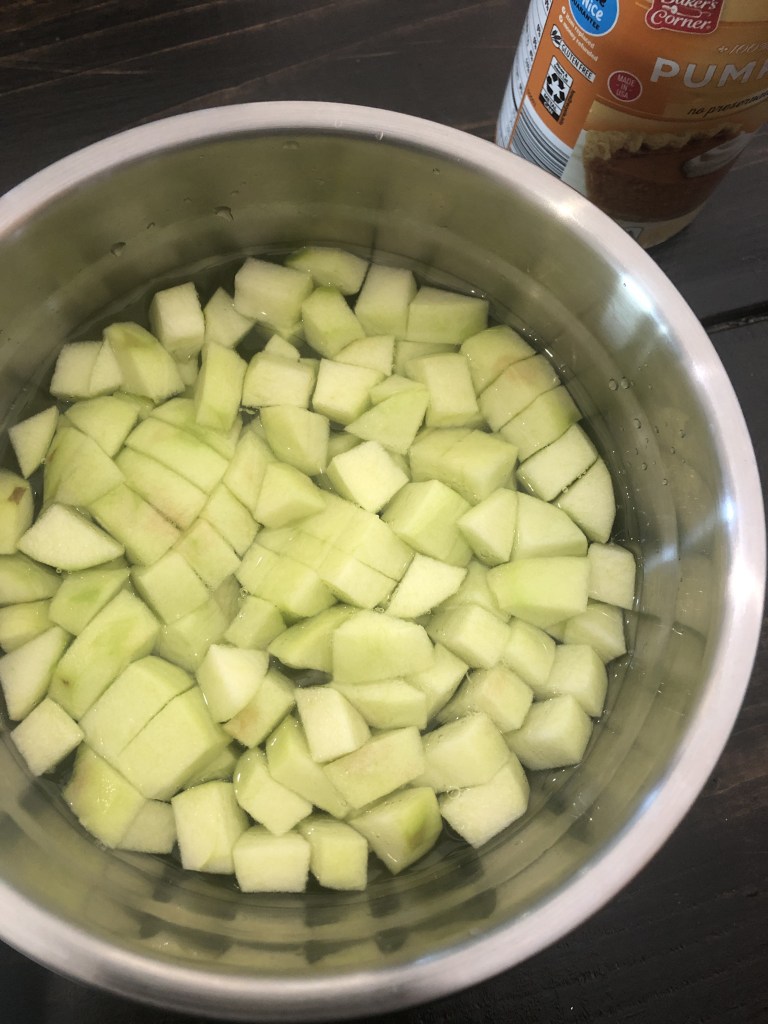 Apples have been diced and submerged in a bowl of water.