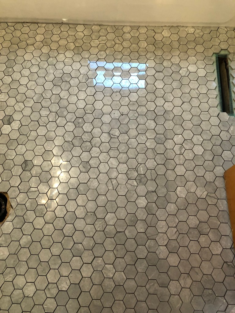 A floor has just been laid with tile as a first step to gauge how tile will look when finished.