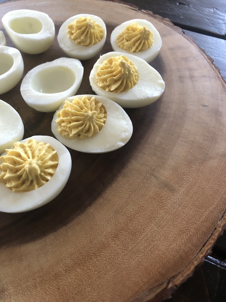 The best deviled egg recipe is being piped together before guests enjoy them.