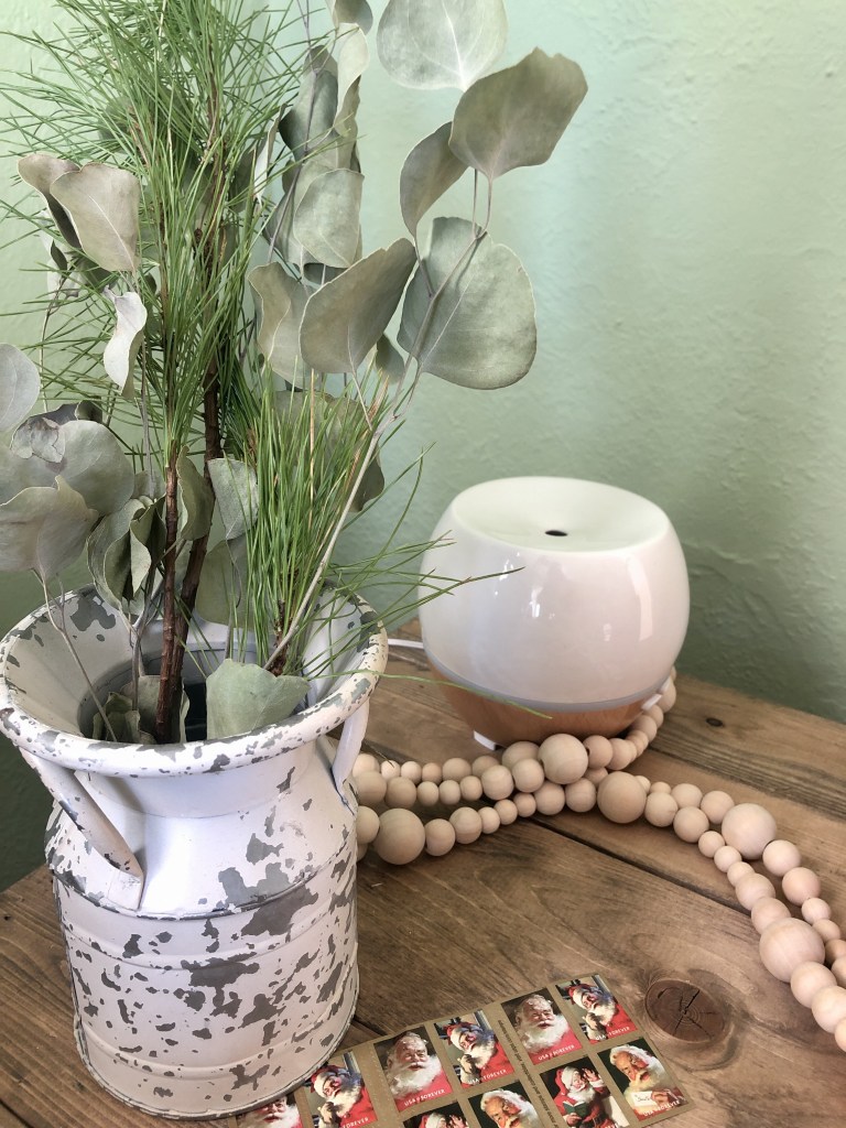 Winter cottage decor consists of Santa stamps and fresh winter foliage in a rustic vase.