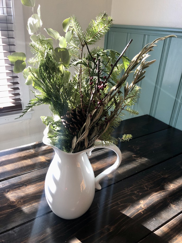 Winter cottage decor is complete with a bouquet of fresh winter foliage on a kitchen dining table.