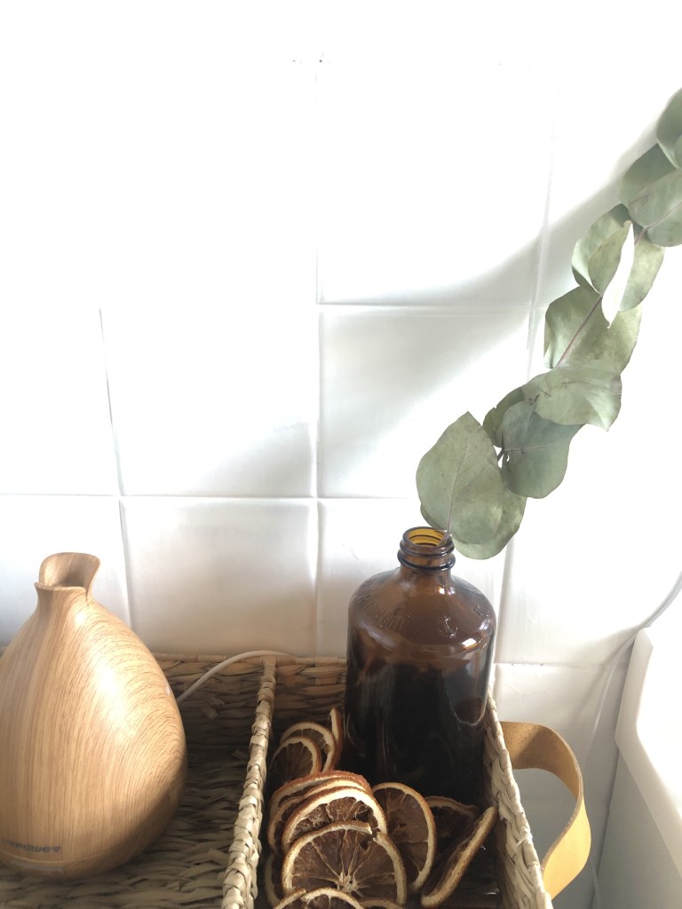 Dried, sliced citrus is placed around an amber vase with a single eucalyptus branch in it for the inter season.