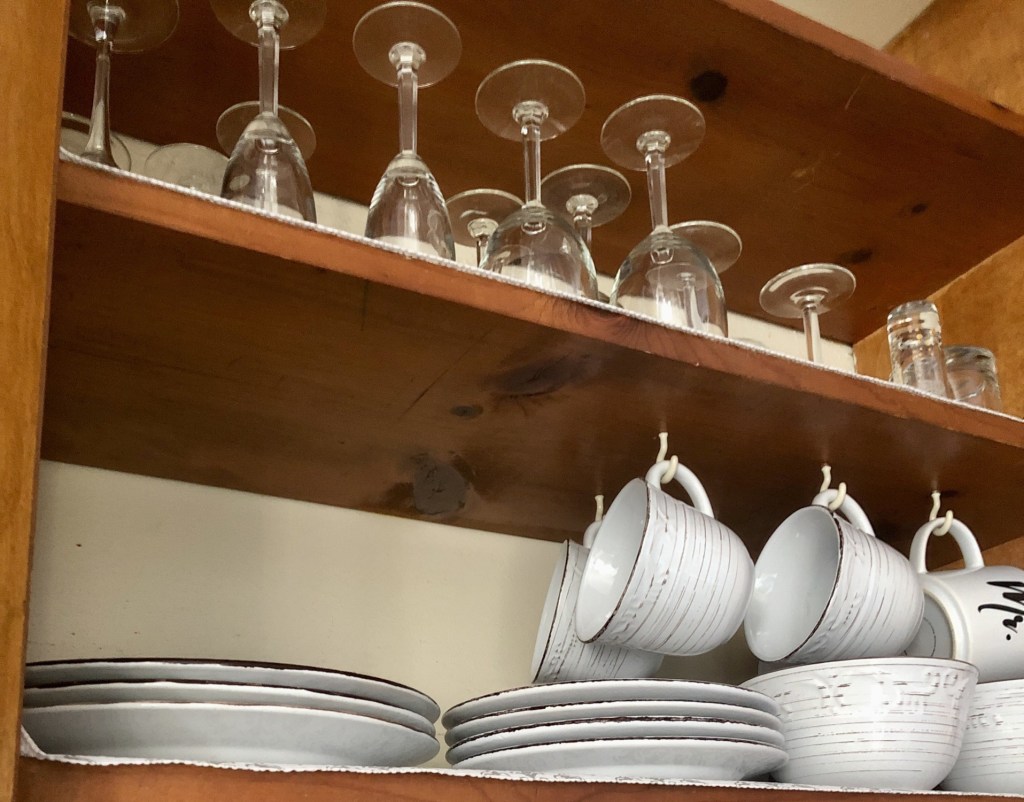 Shelves have perfectly lined up plates and glassware for organization.
