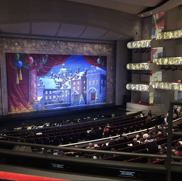 A couple has many winter date ideas, one of which is a ballet. A stage is set with winter decor and ready for The Nutcracker.