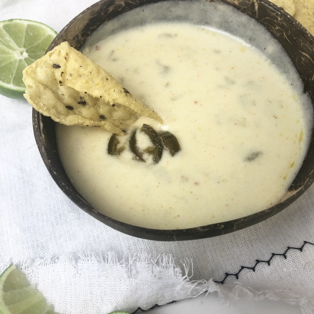 An up-close shot of Super Bowl Queso reveals green chilies and jalapeños as a garnish.