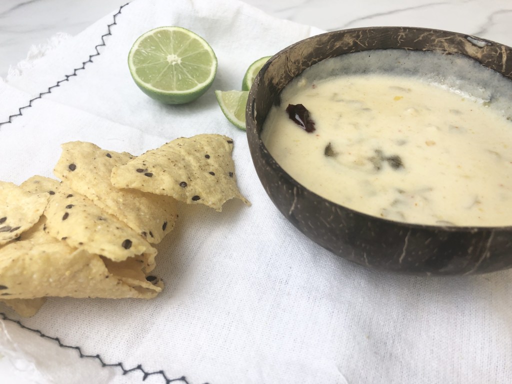 Creamy homemade queso waits to be devoured on a linen on a. tabletop.