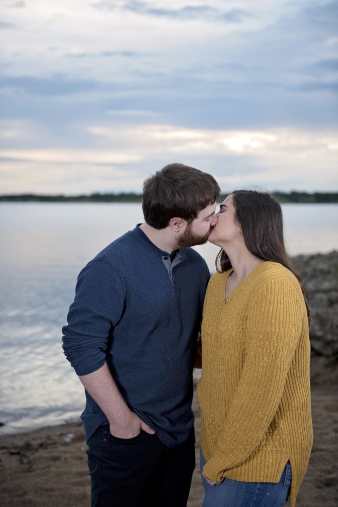 A man and woman kiss as they are newly engaged.