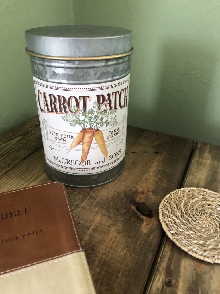 Spring cottage decorating ideas are complete with a carrot patch decorative tin next to a bible.