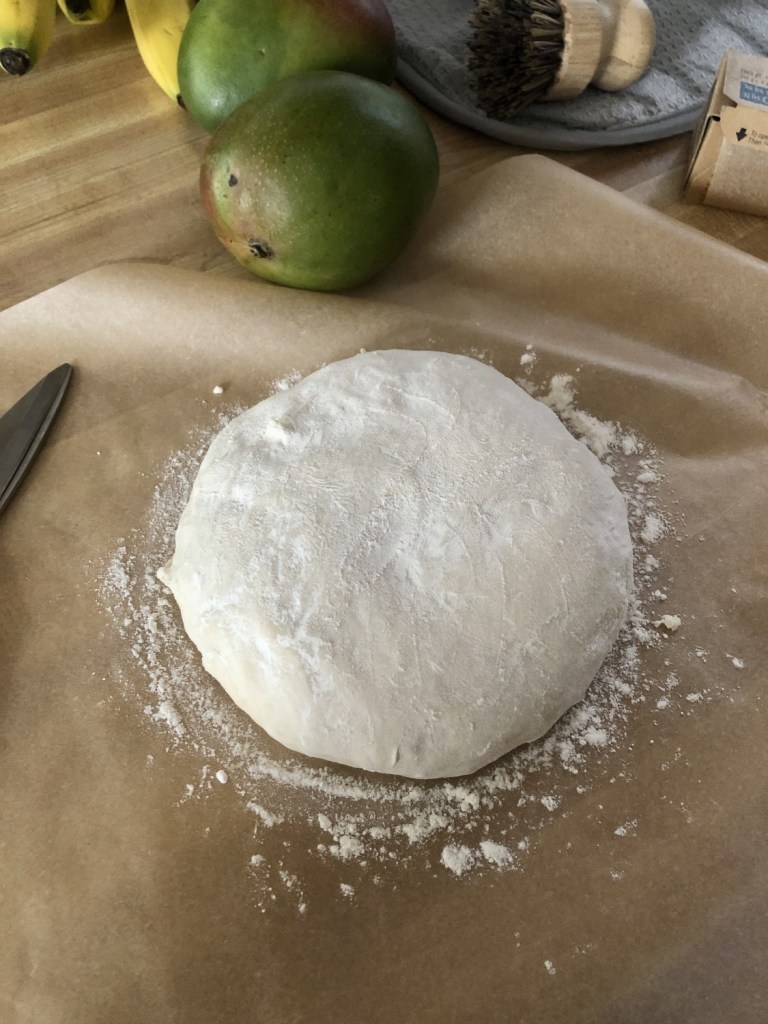 A well floured dough sits on parchment paper waiting to be scored with a bread lame.