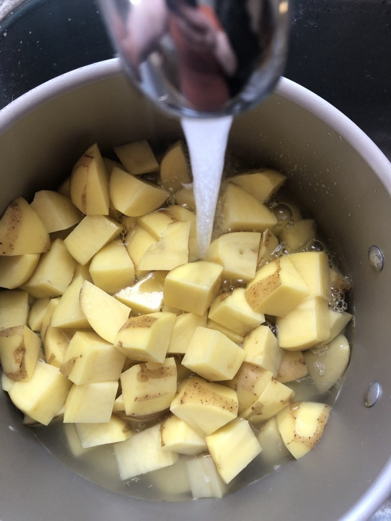 Diced potatoes go into a pot of water to boil before mashing.