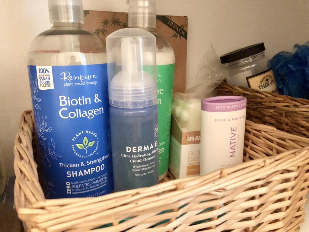 A selection of natural beauty products sits in a clean, white hallway closet nestled into a wicker basket.