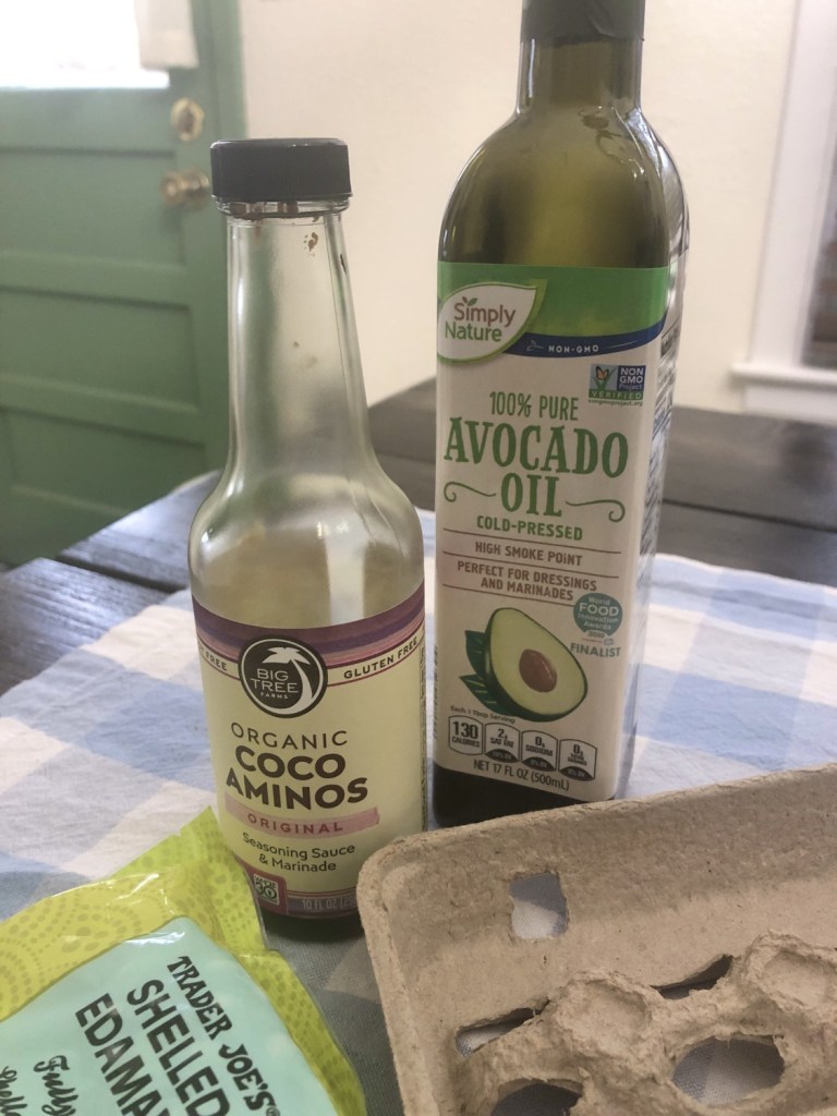 Avocado oil and coconut aminos sit on a tabletop waiting to go into a fried rice dish.