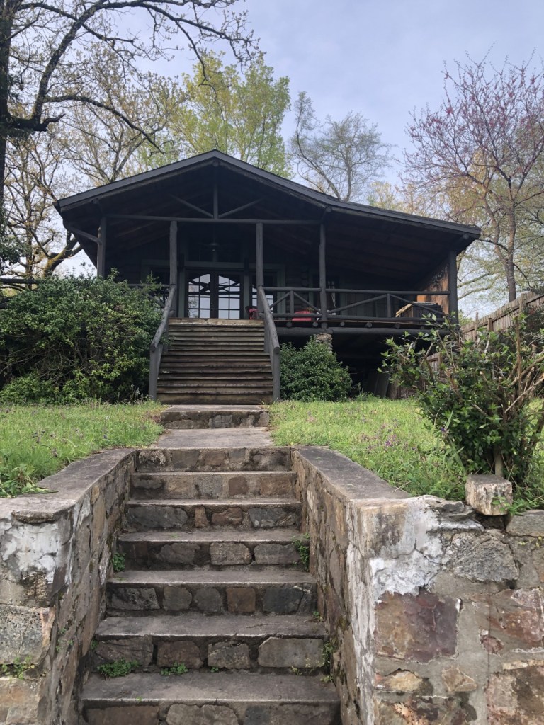 A cabin sits up high on a hill overlooking a lake in Arkansas.