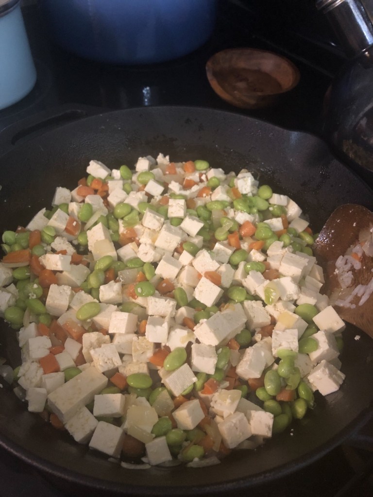 Tofu has been added to a skillet full of veggies.