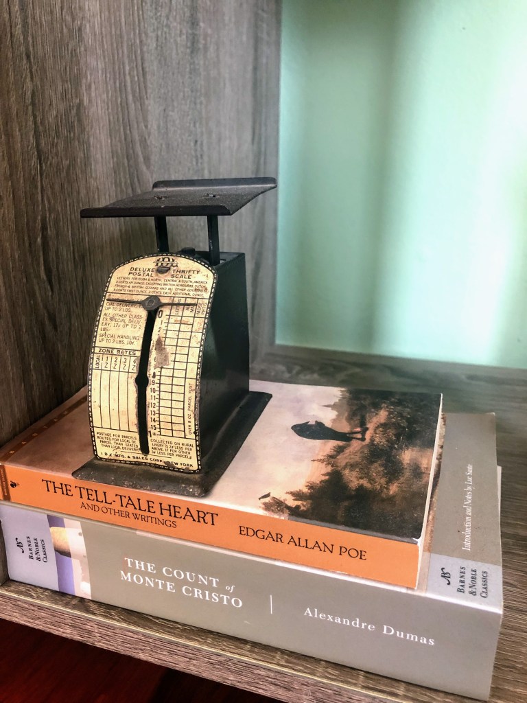A vintage scale and books are placed on a shelf.