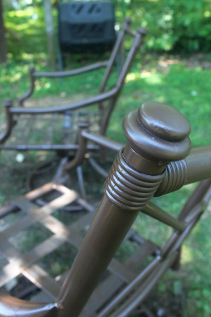 Every spot of two brown patio chairs has been covered in new paint.