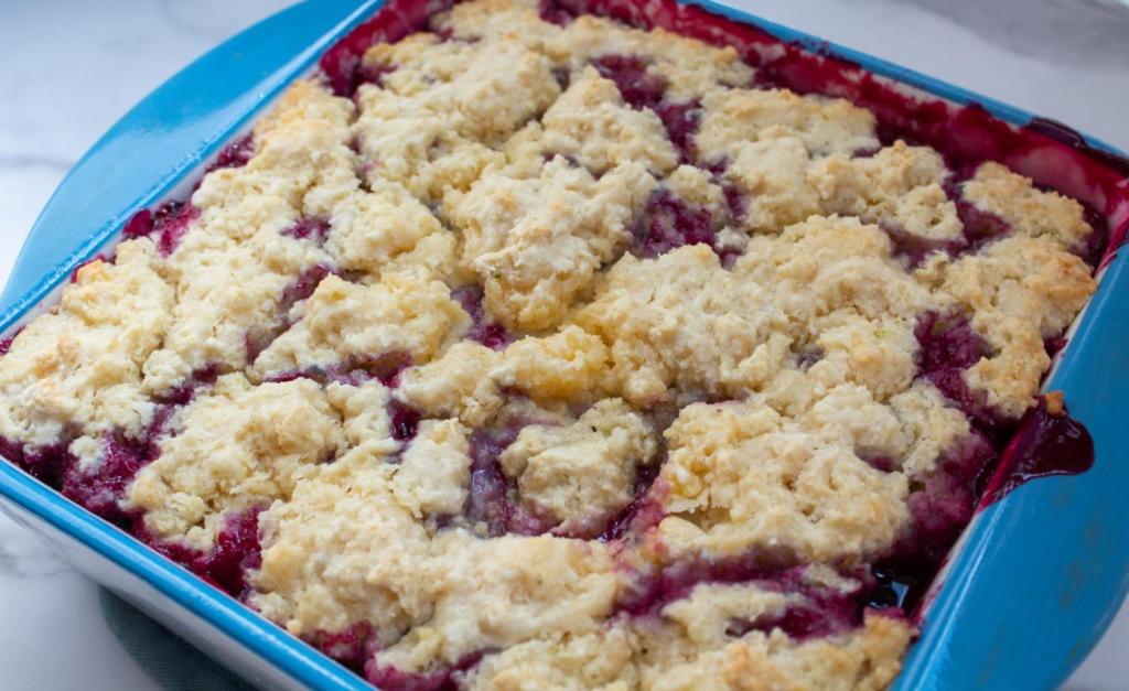 A cobbler has just been pulled from the oven and bubbles in a rich purple sauce.