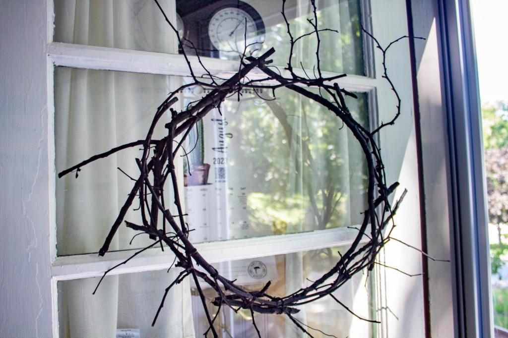 A spooky Halloween wreath is a black branch DIY hanging on a white door.