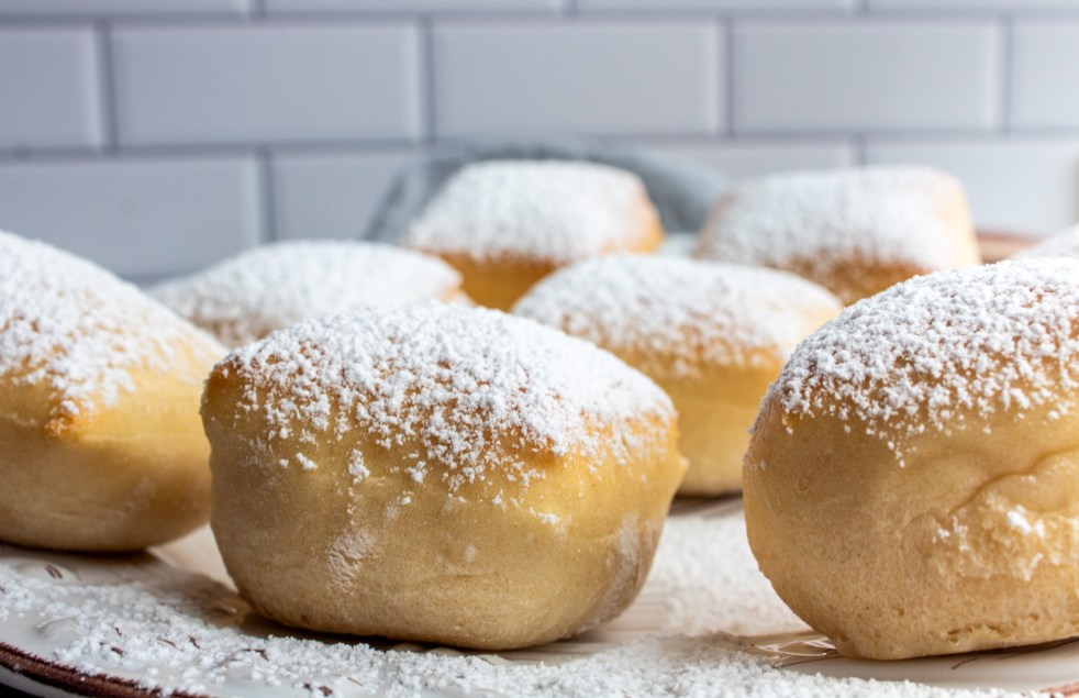 Baked beignet doughnuts recipe are shown up close to show the light, airy thickness of them.