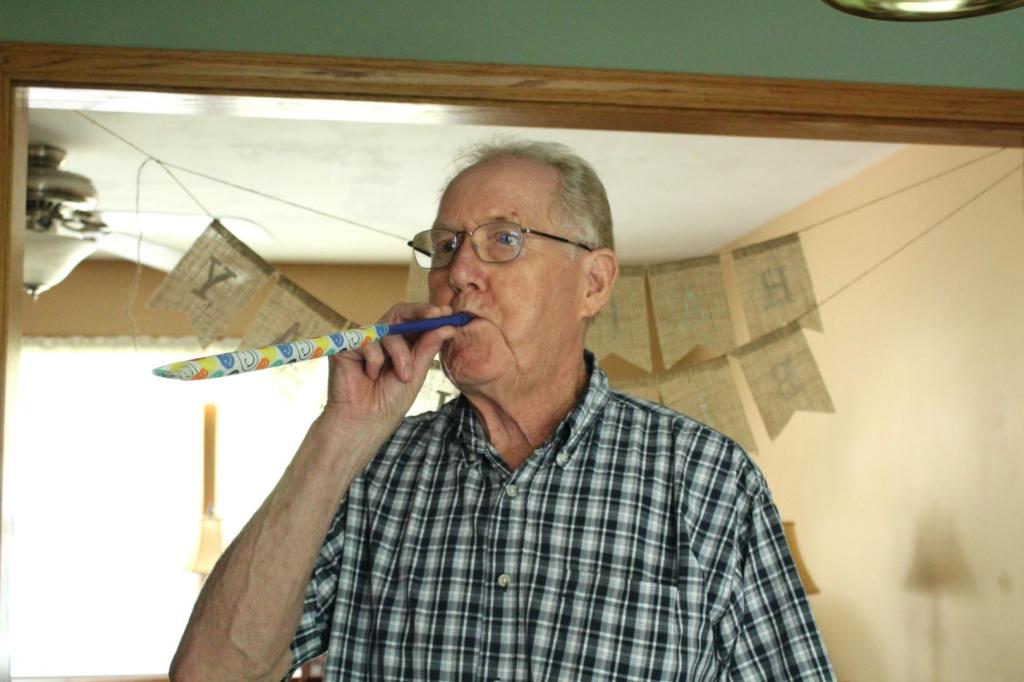 Papa blows on a party blower to celebrate.