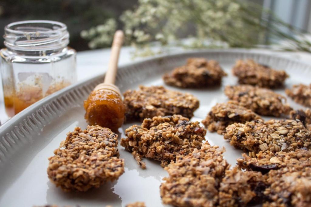 No bake chocolate chip granola bark is served up alongside honey in next to a big open window.