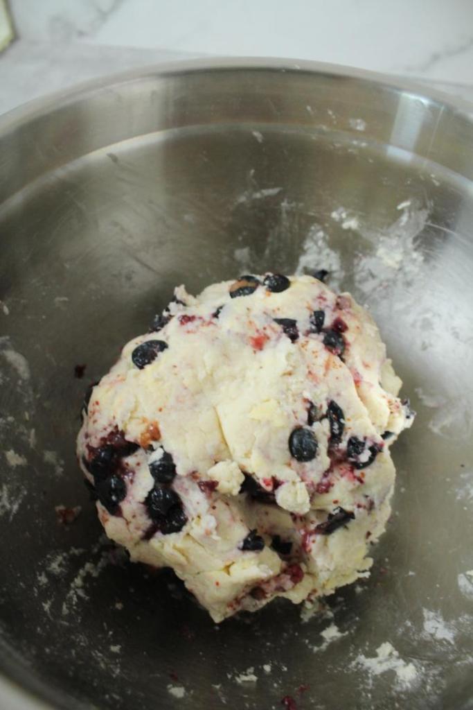 A blueberry scone dough has formed with blueberries in a bowl.
