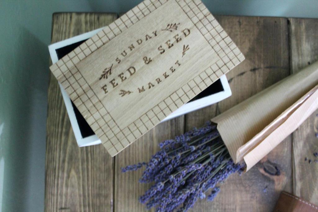 A seed box lays next to a bundle of lavender on a side table.