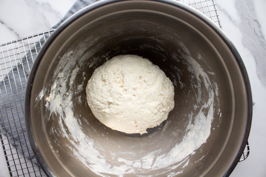A dough forms a ball inside a metal bowl for an easy no yeast bagel recipe.