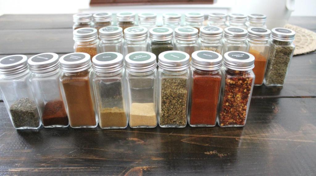 Spice jars have myriad herbs and spices filling them as they're organized into rows.
