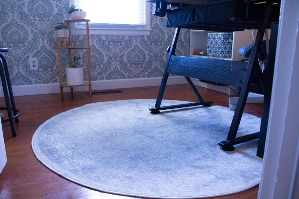 A gorgeous ivory and light blue round rug is centered in a small office.