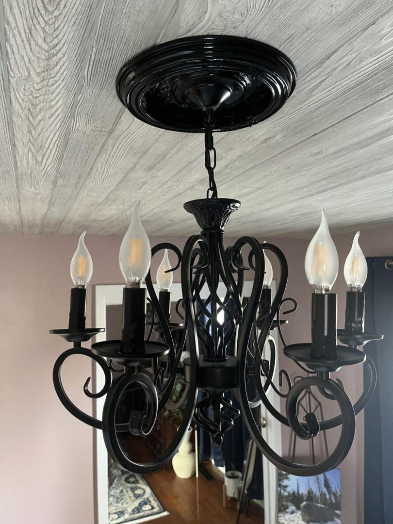 A DIY ceiling medallion is installed above a chandelier in a master bedroom.