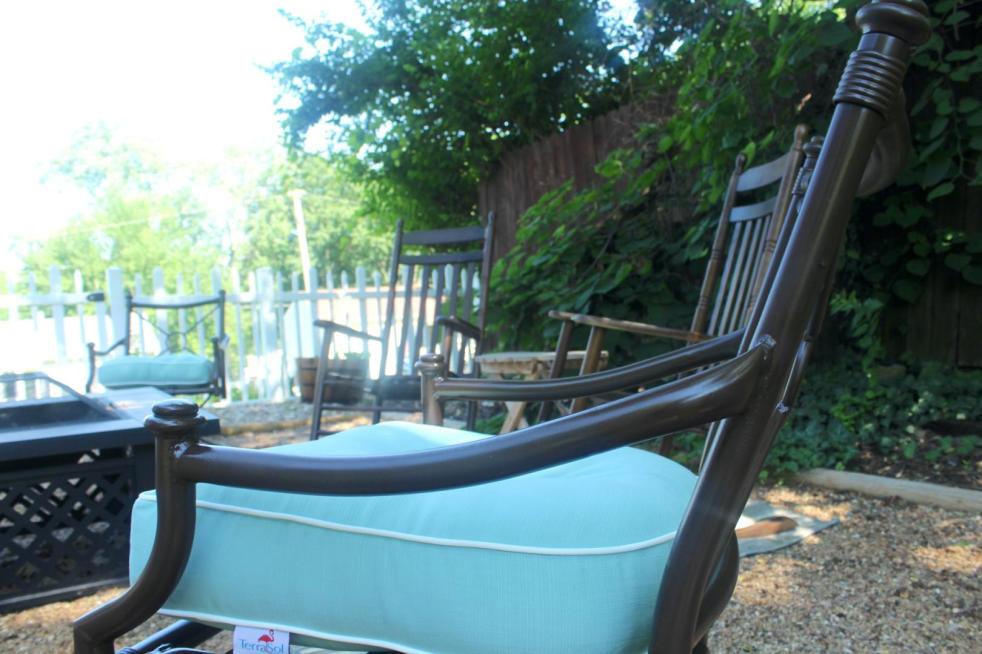 Metal patio furniture is being refinished with new cushion additions that are a blue-green.