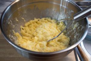 Potatoes are mixed and mashed with other ingredients.