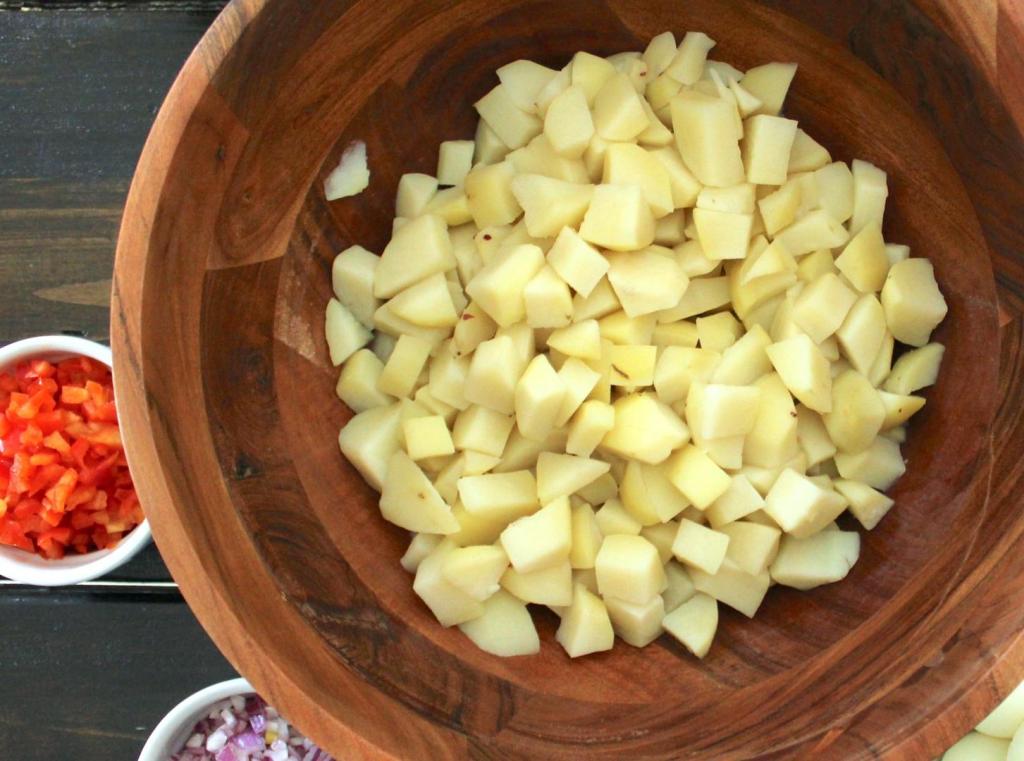 Potatoes sit on a counter next to chopped veggies.