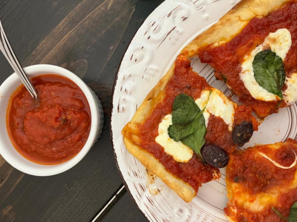 Easy Marinara is spooned into a bowl and spread across a delicious pizza crust.