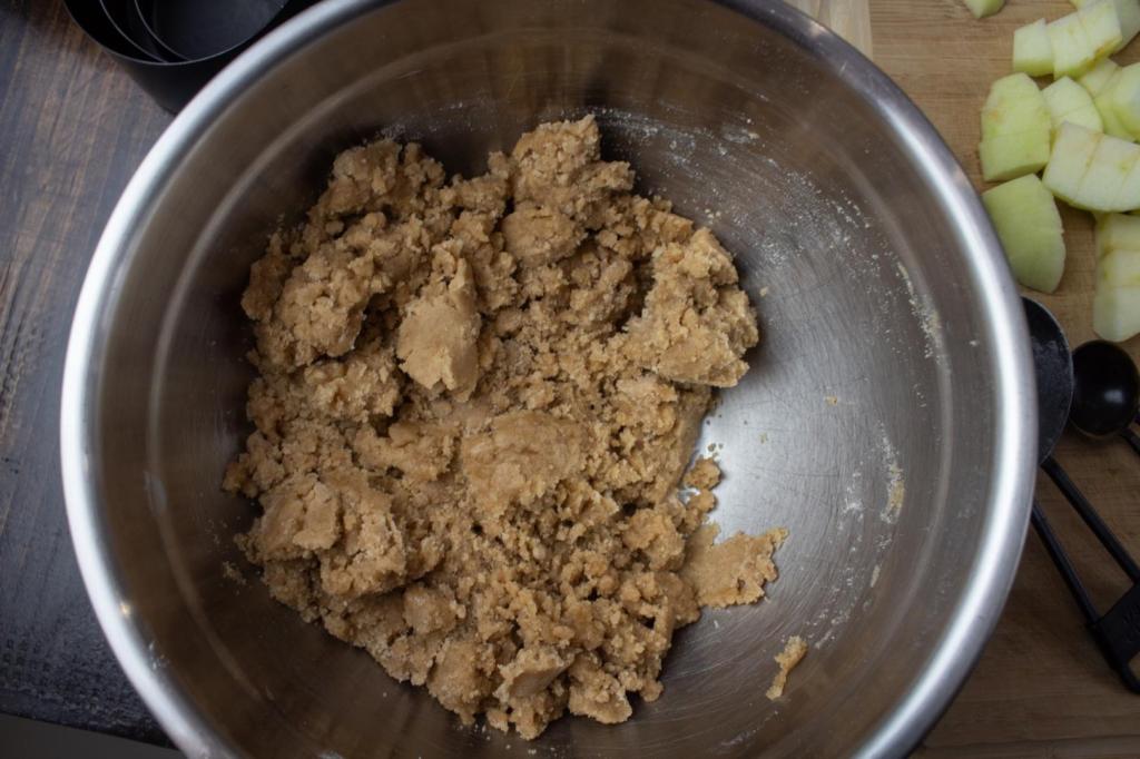 A crumb topping is mixed in a metal mixing bowl.