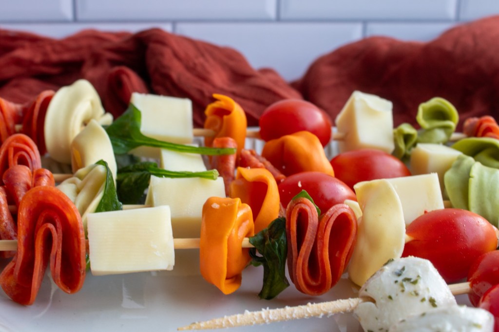 Pepperoni, cheeses, tortellini, olives, basil, and tomatoes are skewered for an easy finger food.