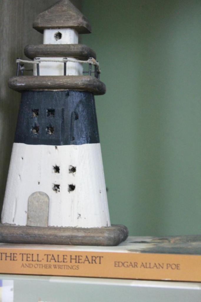 A lighthouse figurine is placed on two classic literature novels.