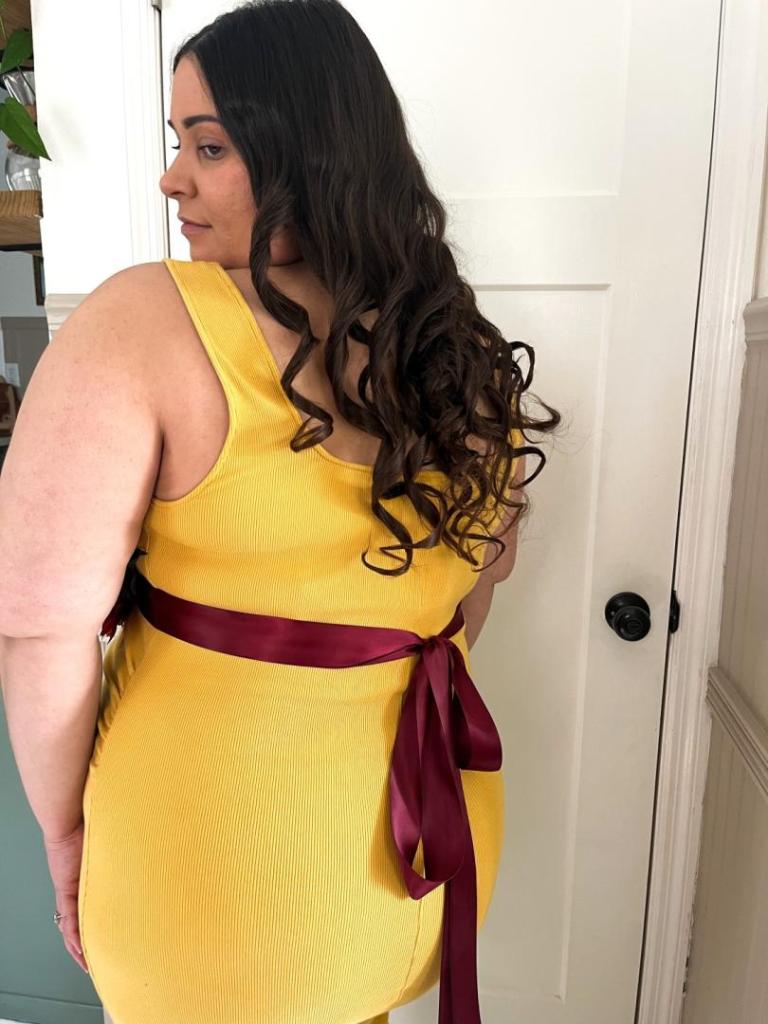 A woman shows the back of a maternity sash belt.