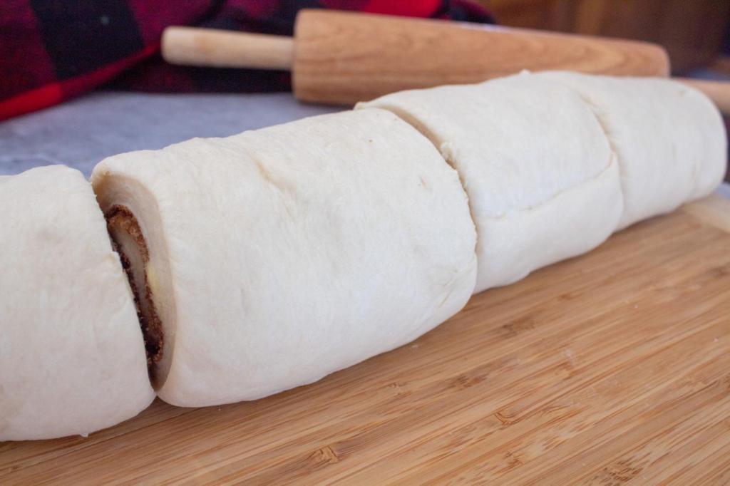 Cinnamon roll dough is sliced into fourths.