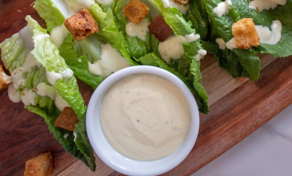 Greek yogurt caesar dressing is dressing romaine lettuce with croutons on a platter.