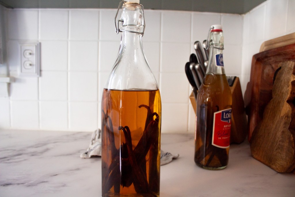 A vanilla extract recipe with vodka is bottled and on a counter next to another bottle.