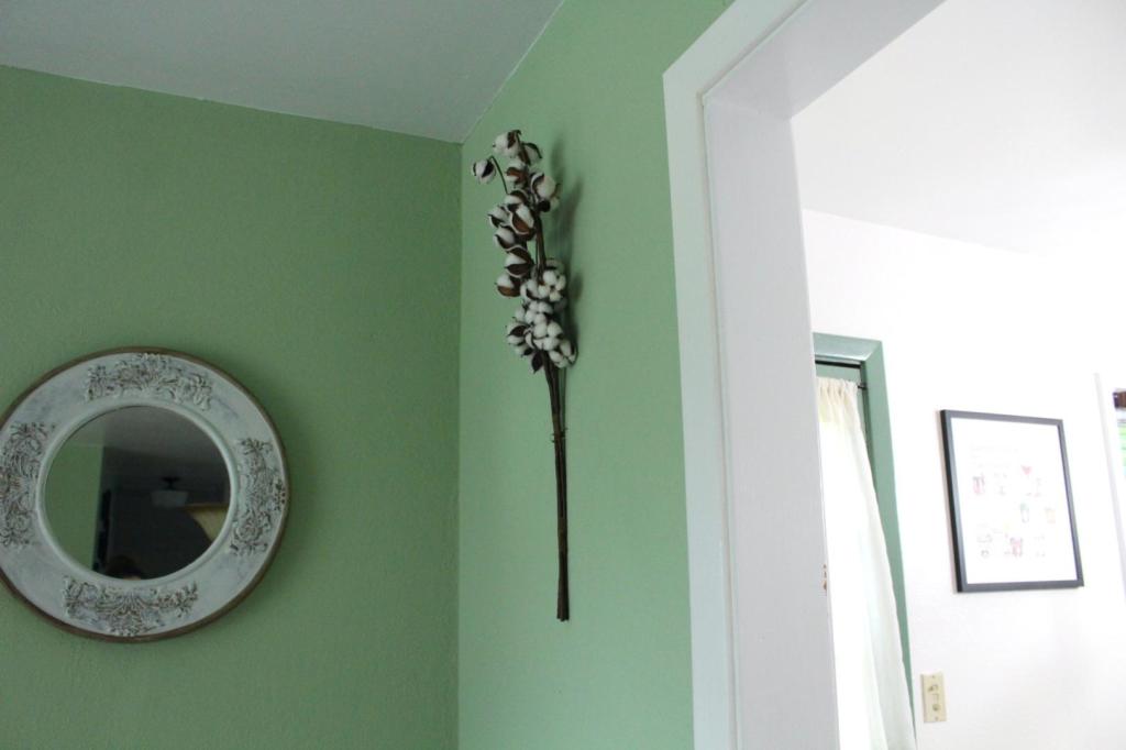 A bundle of cotton hangs on a wall near a vintage mirror.