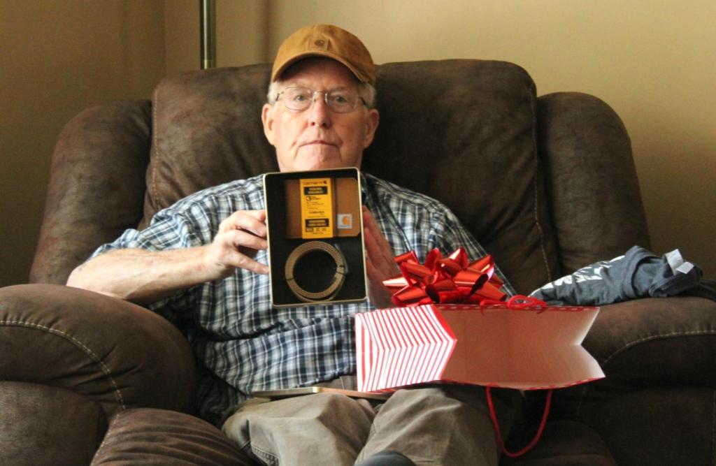 Papa sits in a chair and shows off his new gifts for his birthday.