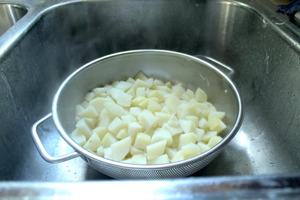 Potatoes are drained in a colander in a sink.