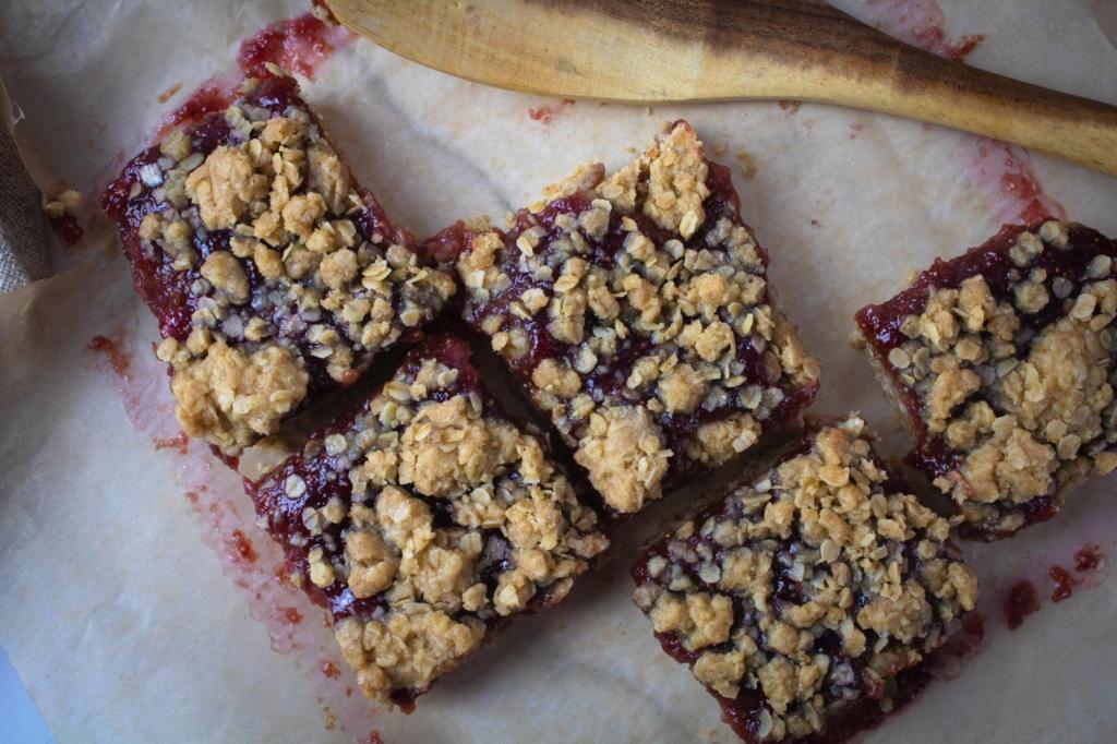 Breakfast bars are being served with a wooden spatula from parchment paper.