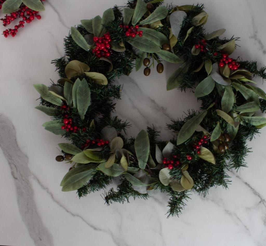 A DIY Christmas wreath is decked out with holly berries and eucalyptus and olive branches.