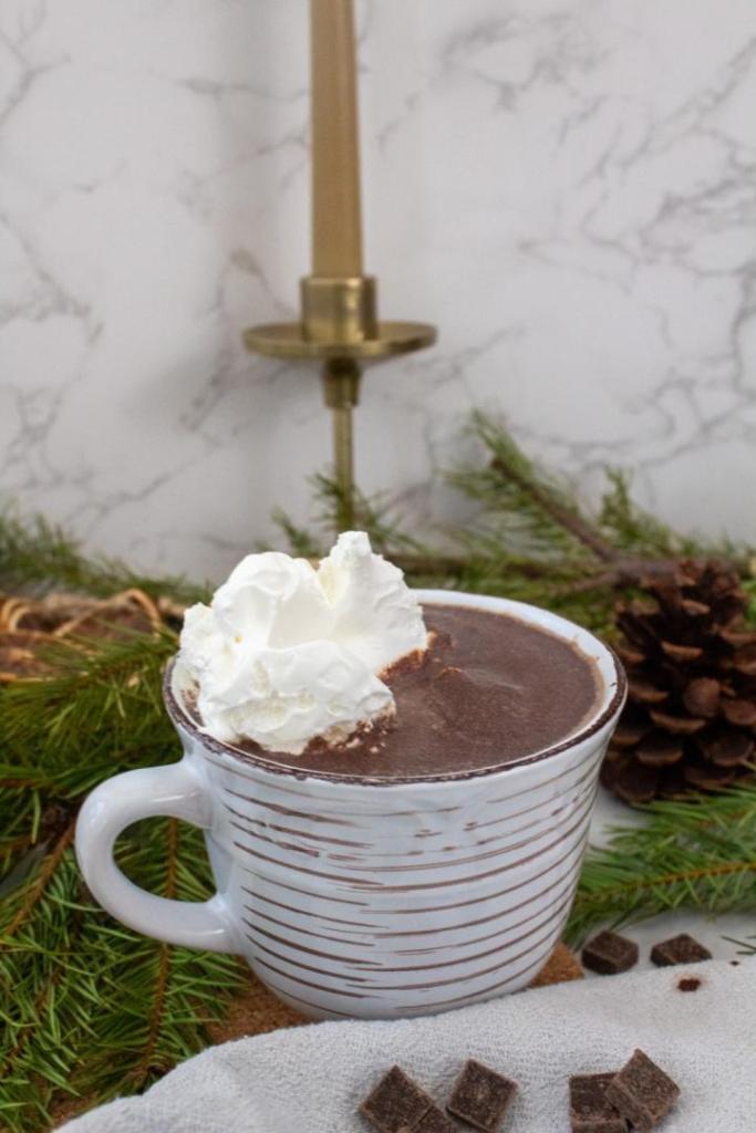 Hot chocolate is filled into a mug and topped with whipped cream.